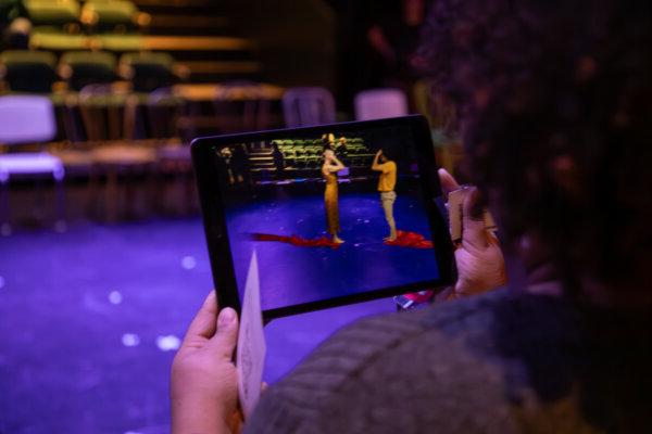 在格莱兹工作室剧院，一名观众使用iPad观看虚拟舞者在舞台上表演